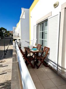 a wooden table and two chairs on a balcony at Cabanas Wonder - 150mts from the beach in Cabanas de Tavira