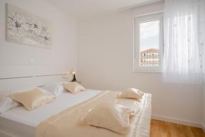 biała sypialnia z łóżkiem i oknem w obiekcie Luxury Apartment Solinka With Private Parking w mieście Solin