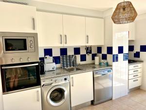 a kitchen with white cabinets and a washing machine at Cabanas Wonder - 150mts from the beach in Cabanas de Tavira