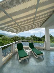 2 sillas verdes en el balcón de un edificio en Villa Carmela, en Palinuro
