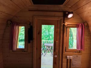 a room with two windows and a door in a cabin at Fasshotel Westernwagen, beheizt 2-3 Personen in Kirchensittenbach
