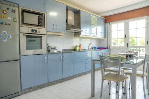 una cocina con armarios azules y una mesa con sillas en Apartamento Ultreia en Palas de Rei 