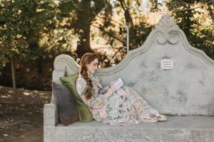 a woman sitting on a stone bench reading a book at Weltevreden Estate in Stellenbosch