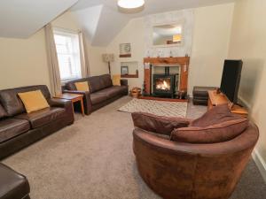 a living room with leather furniture and a fireplace at Cheviot Hills in Wooler