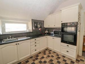 a kitchen with white cabinets and black counter tops at Cheviot Hills in Wooler
