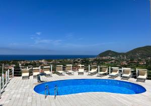 a swimming pool with chairs and a view of the ocean at infinity Castellabate b & b di Charme in Santa Maria di Castellabate
