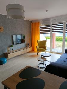 uma sala de estar com um sofá azul e uma televisão em Apartament Claudia em Darlowko