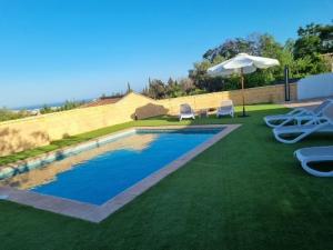 a swimming pool with two lawn chairs and an umbrella at FINCA VALENZUELA in Mijas