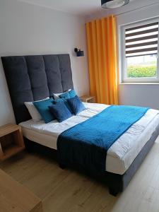 - une chambre avec un grand lit et des oreillers bleus dans l'établissement Apartament Claudia, à Darłówko