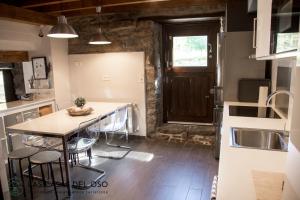 a kitchen with a table and chairs and a sink at El Torreón - Las Casas del Oso in Proaza