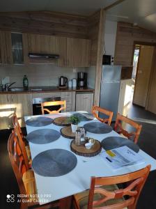 a kitchen with a white table with chairs and a tableablish at Domek letniskowy - niebieski całoroczny in Stegers