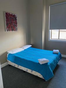 um quarto com uma cama com lençóis azuis e uma janela em Australian Hotel Young em Young