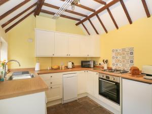 a kitchen with white cabinets and a stove top oven at 3 Lake Cottages in Cheltenham