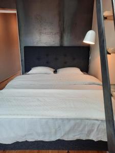a bedroom with a large white bed with a black headboard at Gîte l'Atelier agréable maison de ville avec cour intérieure in Saint-Hubert