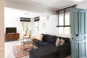 ein Wohnzimmer mit einem Sofa und einem TV in der Unterkunft SV Acropolis Residence in Athen