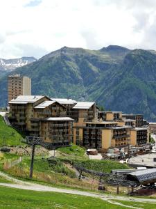 un grand bâtiment avec des montagnes en arrière-plan dans l'établissement Résidence les Terrasses De La Bergerie (by Sabine et JeanKry), à Orcières