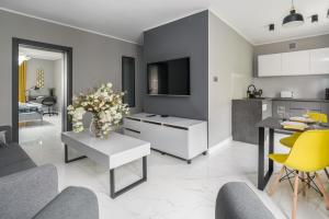 salon z kuchnią i stołem z kwiatami w obiekcie Chociszewskiego Apartment Poznań by Noclegi Renters w Poznaniu