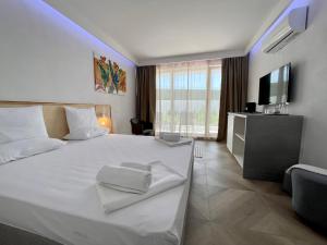 a bedroom with a large white bed and a television at JI HOTEL in Sozopol