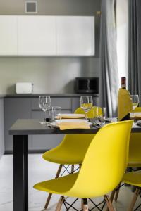 stół jadalny z żółtymi krzesłami i kieliszkami do wina w obiekcie Chociszewskiego Apartment Poznań by Noclegi Renters w Poznaniu