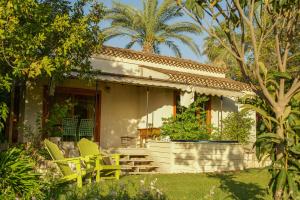 a house with two yellow chairs in front of it at Hanahala Beramot - Boutique Suites in Moshav Ramot