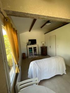 1 dormitorio con cama blanca y ventana en Cabanon entouré de montagnes et d'oliviers, en Nyons