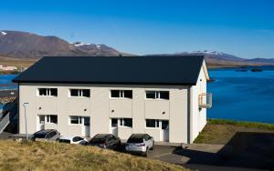 a white building with cars parked in a parking lot at Salth&uacute;s Guesthouse in Skagastr&ouml;nd