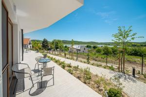 een patio met een tafel en stoelen en uitzicht op een rivier bij Hérics Apartman in Tihany