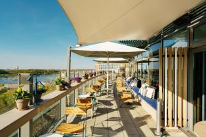 a patio area with tables, chairs and umbrellas at Radisson Blu Hotel Rostock in Rostock
