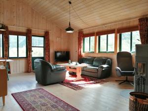 a living room with leather couches and a tv at Reinunga Eco-hytta in Myrdal