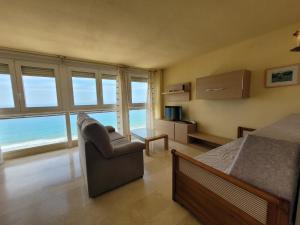 a bedroom with a bed and a chair and the ocean at Santa Margarita-Fincas Benidorm in Benidorm