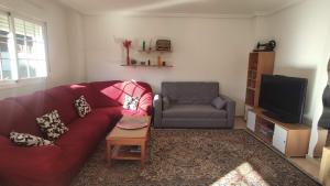 een woonkamer met een rode bank en een stoel bij Warner,piscina, aire ac, barbacoa, chillout, 400m patio in Seseña