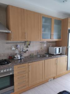 a kitchen with wooden cabinets and a sink and a microwave at Ria´s Relax in Alvor +5 photos