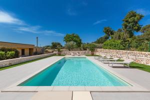 a swimming pool with chairs and a stone wall at Villa Trulli Natura by BarbarHouse in Noci