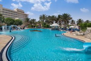 a swimming pool in a resort with blue water at Radisson Blu Hotel & Resort, Al Ain in Al Ain
