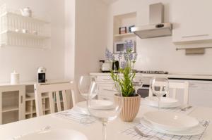 biała kuchnia ze stołem z talerzami i kieliszkami do wina w obiekcie [ApuliaLux] Panta Rei Luxury House nel Centro Storico w mieście Altamura