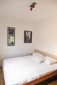 a white bed in a bedroom with two pictures on the wall at Divine in Budva