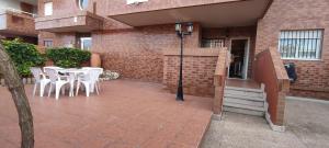 patio z białymi krzesłami i stołem oraz budynek w obiekcie ACV - Playa Coral II-2ªlinea planta baja norte w mieście Oropesa del Mar