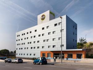 a white building with a car parked in a parking lot at B&B HOTEL Barcelona Granollers in Les Franqueses del Vallès