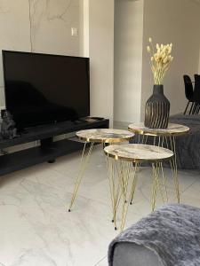 a living room with two tables and a tv at Oneiro Napa Suite in Ayia Napa