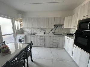 a kitchen with white cabinets and a table and a microwave at Oneiro Napa Suite in Ayia Napa