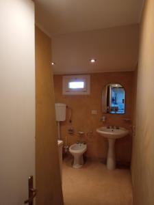 ein Badezimmer mit einem Waschbecken, einem WC und einem Spiegel in der Unterkunft Liama Macchia degli Specolizzi in Lido Marini