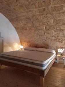 Bett in einem Zimmer mit Ziegelwand in der Unterkunft Liama Macchia degli Specolizzi in Lido Marini