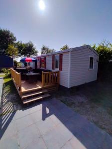 a tiny house with a deck and a patio at BJ Chalets - Robbengat 68 - Gezellige, kindvriendelijke chalet op vakantiepark Lauwersoog! Vroege incheck! in Lauwersoog