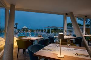 a restaurant with tables and chairs with a view of a pool at Hotel Delle Rose in Lido di Jesolo