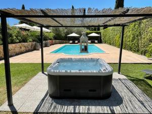a hot tub under a pergola next to a swimming pool at Abbadia Sicille Relais in Trequanda