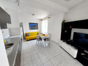 uma cozinha e sala de estar com uma mesa e um sofá amarelo em Apartman Darija em Preko