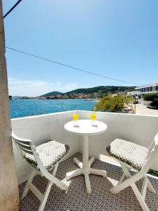 uma mesa branca e 2 cadeiras com bebidas numa varanda em Apartman Darija em Preko