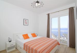 a white bedroom with a bed and a balcony at Vista Apartments in Cavtat