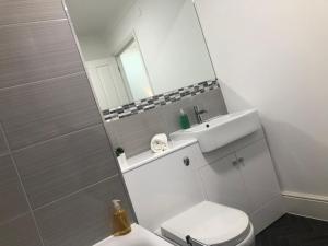 ein Badezimmer mit einem WC, einem Waschbecken und einem Spiegel in der Unterkunft 2 Bedroom Apartment in Central Windsor in Windsor