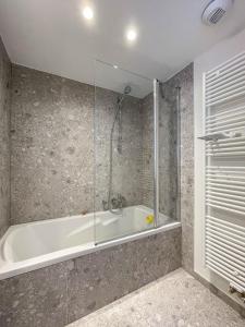 een badkamer met een bad en een glazen douche bij Residentie Square - Nieuwbouw - 50 m van de zee in Knokke-Heist